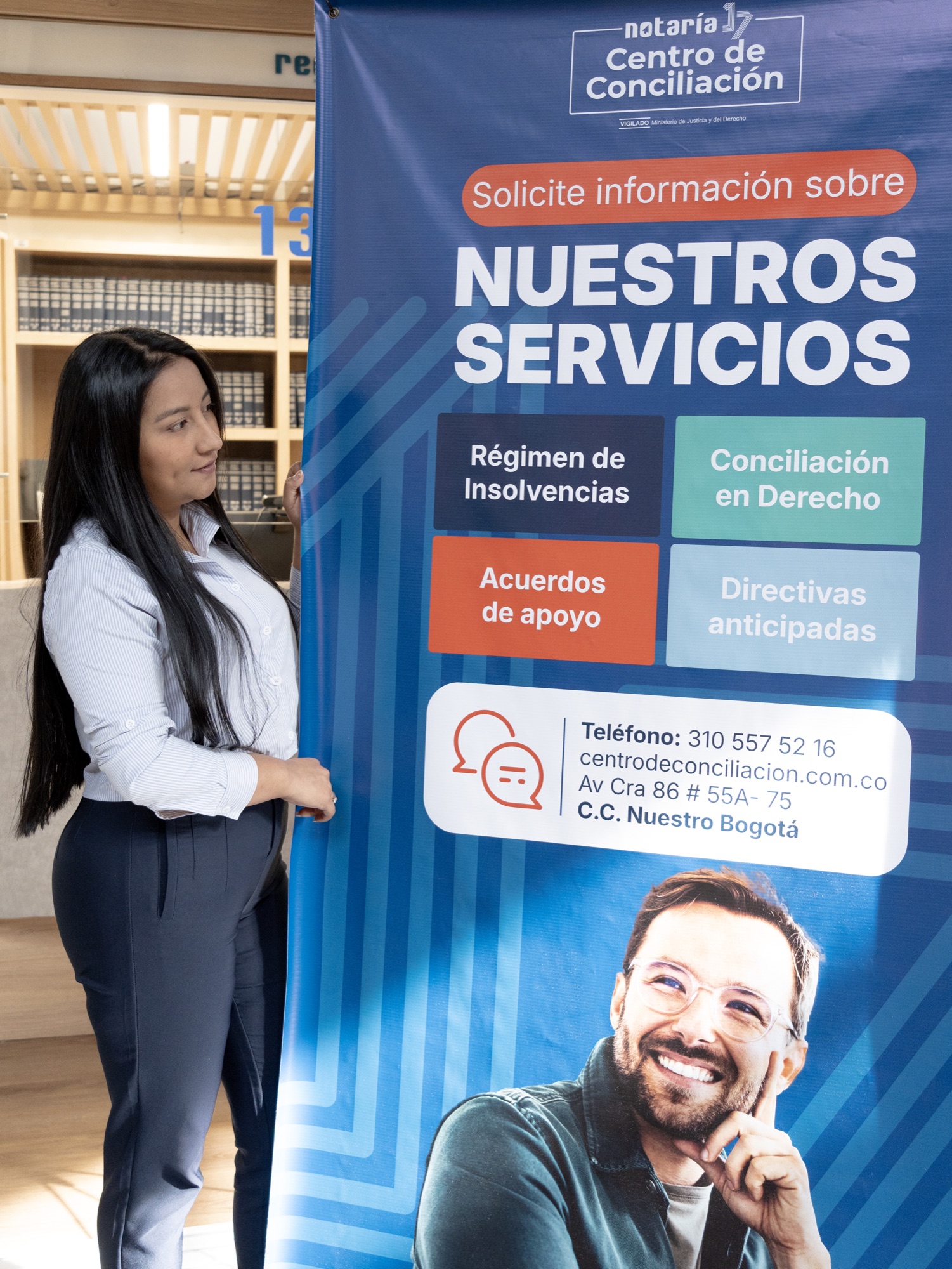 Funcionaria junto al pendón de servicios del Centro de Conciliación de la Notaría 17 de Bogotá